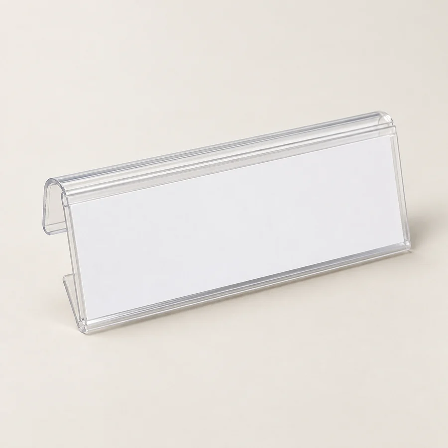 Clear shelf-edge label holder with plain blank white insert, three-quarter view.